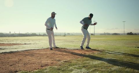 Two Baseball Players Practicing Pitching Drill on Sunlit Field at Dawn