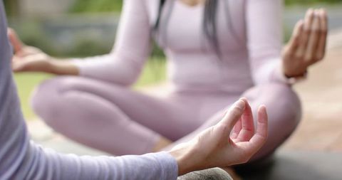 Women meditating outdoors on patio in pastel activewear practicing mindfulness, mudra and serenity