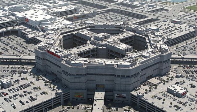 Octagonal multilevel parking garage dominating suburban retail complex, aerial view