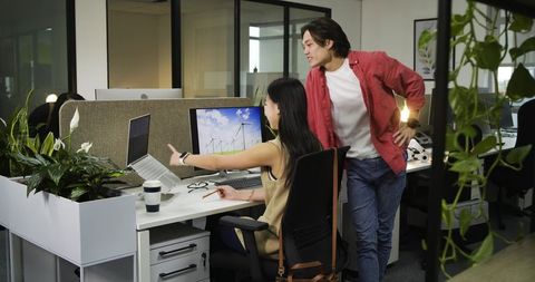 Diverse Coworkers Discussing Project in Green Office Environment