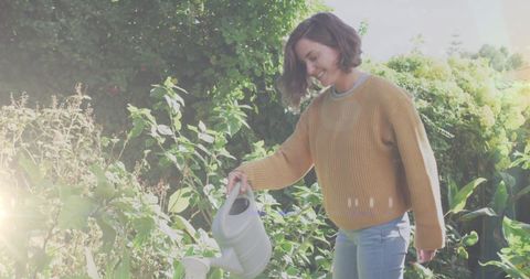 Caucasian Woman Watering Garden in Bright Sunlight