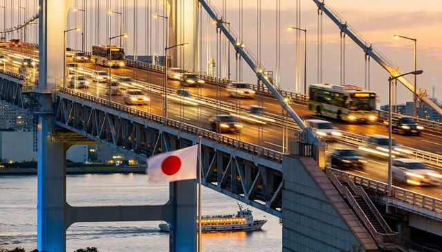 Dusk Traffic on Suspension Bridge with Japanese Flag, Bus and Harbor Light Trails