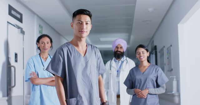 Group of diverse healthcare workers standing in hospital corridor, smiling confidently. Ideal for promoting healthcare services, illustrating teamwork in healthcare, and highlighting diversity in medical professions.