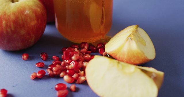 Image of honey in jar, cranberries, apples and apple slices lying on blue surface. food, cooking, baking, taste and flavour concept.