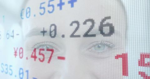 Mid-adult woman's eyes reflecting financial data on translucent digital display
