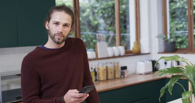 Young Man Holding Phone in Modern Kitchen - Download Free Stock Images Pikwizard.com