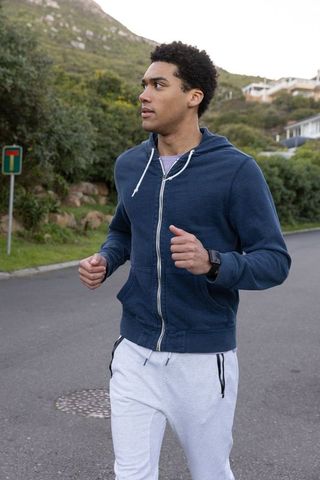 Man running on scenic hillside road wearing smartwatch