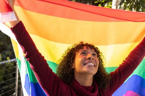 Joyful Woman Celebrating LGBTQ+ Pride with Vibrant Rainbow Flag
