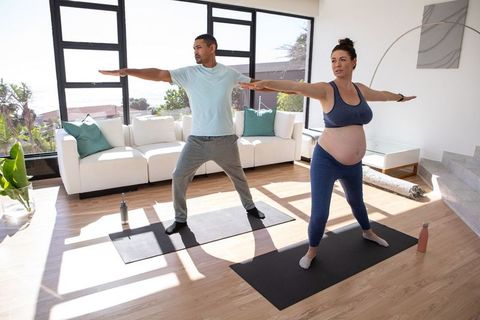 Pregnant Woman and Partner Holding Yoga Poses at Home During Workout