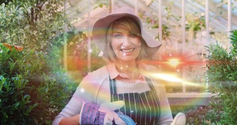 Joyful Gardener Watering Plants in Greenhouse with Sun Hat and Apron