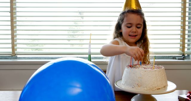 Girl placing candles over birthday cake at home