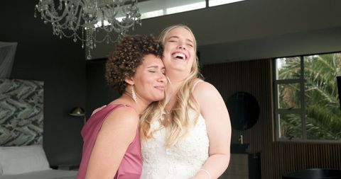 Joyful bride and bridesmaid sharing moments before wedding ceremony