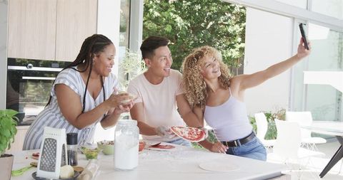 Diverse Friends Making Pizza and Taking Selfie in Bright Kitchen