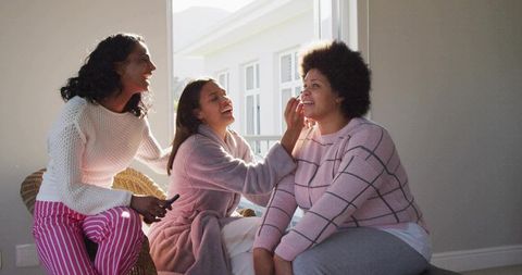 Friends applying makeup during cozy morning routine at home beauty bonding