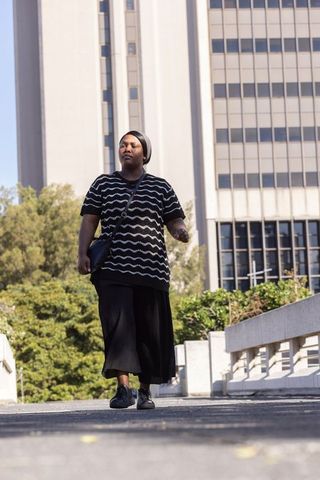 African american woman walking on downtown elevated walkway carrying crossbody bag