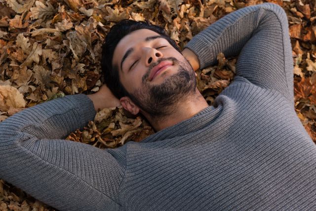 Overhead of man sleeping on autumn leaves