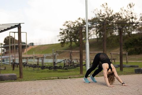 Woman in sportswear practicing downward dog pose outdoors