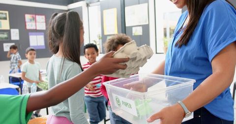 Children Recycling Paper in Classroom with Teacher Guidance