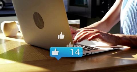 Woman typing on laptop with social media likes notification bubble and coffee mug