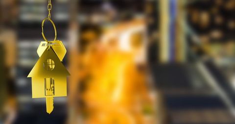 Golden house keys hanging over cityscape symbolizing real estate success