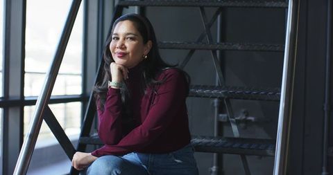 Contemplating professional woman sitting on industrial metal staircase in loft