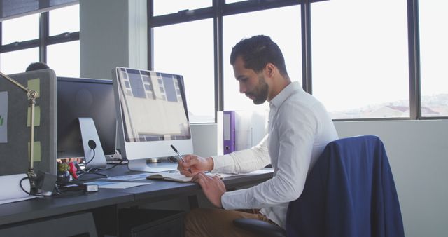 Focused Businessman Writing Notes at Desk in Modern Office - Download Free Stock Images Pikwizard.com