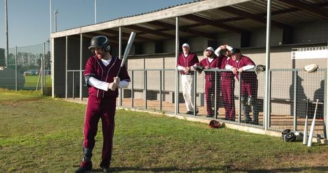 Baseball Team Awaiting Turn at Bat Near Dugout