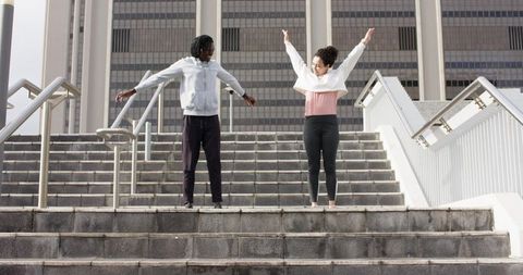 Diverse friends stretching arms on urban stairs warming up for outdoor workout and training