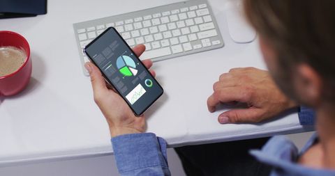 Man analyzing statistics on smartphone at desk
