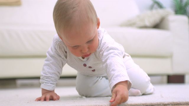 Adorable baby in casual setting examines a plush white carpet, conveying curiosity and discovery. Use in articles about child development, safe home environments, and parenting tips.