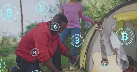 Outdoor camping couple pitching tent with acoustic guitar and bitcoin crypto overlay