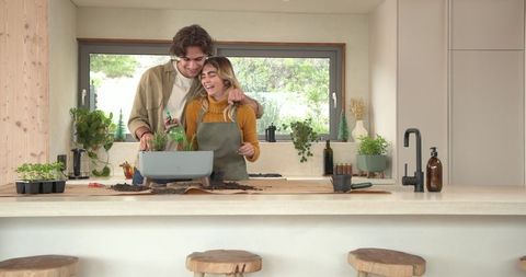 Female Friends Gardening Indoors with Herb Seedlings in Kitchen