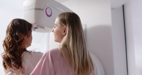 Radiology technician positioning patient for mammogram, compassionate breast imaging care
