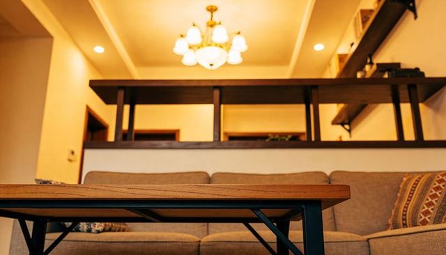 Low-angle wooden coffee table dominating cozy living room, evoking warm ambient lighting