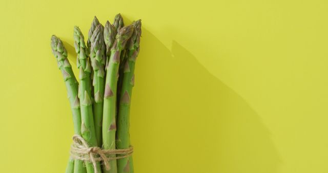 Image of bundle of fresh asparagus with copy space over green background. fusion food, fresh vegetables and healthy eating concept.