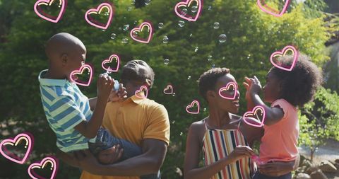 Joyful African American Family Making Bubbles Outdoors