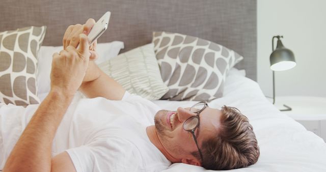 Smiling Young Man Using Smartphone in Cozy Bedroom - Download Free Stock Images Pikwizard.com