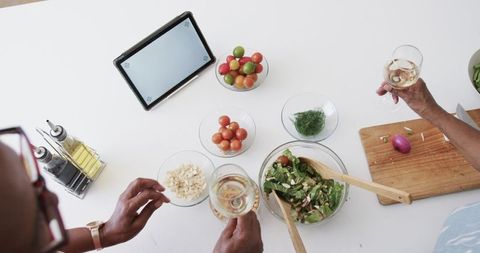 Senior Friends Enjoy Cooking with Fresh Vegetables and Wine