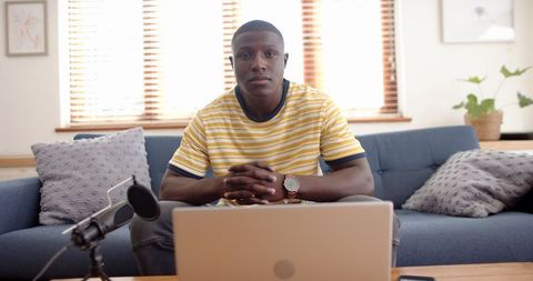 Man Podcasting from Home with Laptop and Microphone Setup