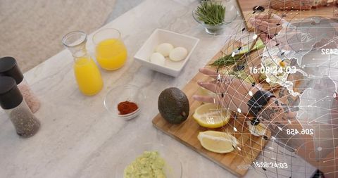 Hands chopping avocado and slicing lemons on marble countertop with digital globe overlay