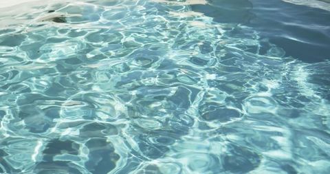 Sunlit turquoise pool water rippling with caustic light and reflective shimmer