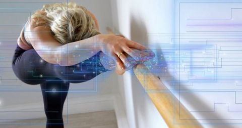 Balancing dancer stretching at barre, displaying poise and flexibility with blue digital overlay