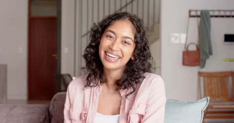 Smiling Woman Relaxing on Sofa at Home in Light-Filled Living Room