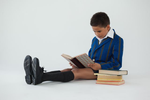 Attentive schoolboy reading book on white background