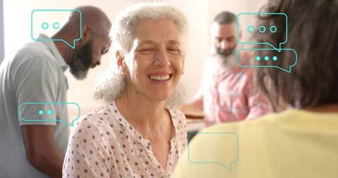 Smiling senior woman enjoying lively multigenerational kitchen conversation with friends
