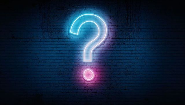 Neon Question Mark Sign Glowing on Dark Brick Wall