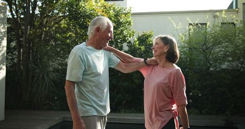 Happy senior couple stretching outdoors in casual athletic wear