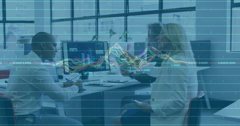 Business team analyzing market trends on dual monitors in modern office