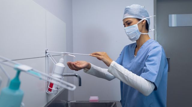 Side view of female surgeon using hand wash in bathroom at hospital