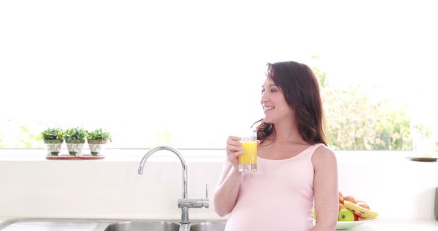 Pregnant Woman Enjoying Orange Juice in Bright Kitchen - Download Free Stock Images Pikwizard.com